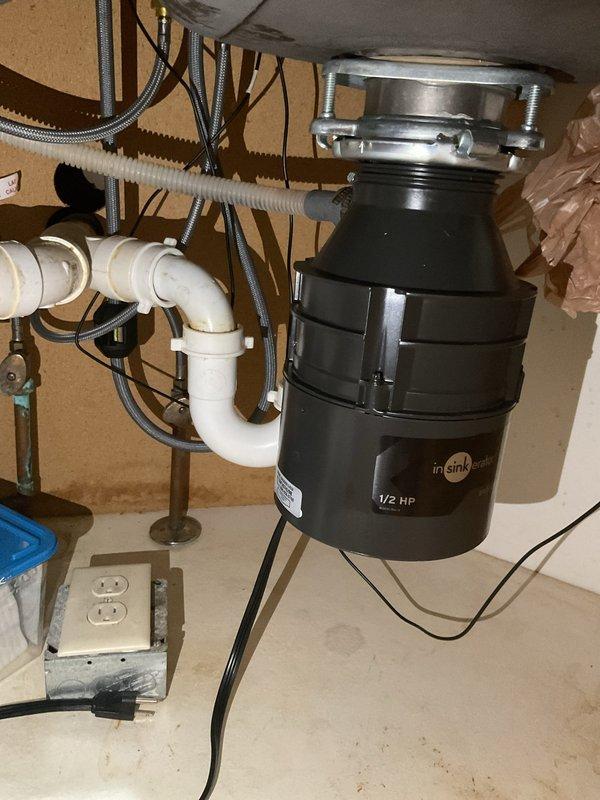 Installed new InSinkErator 1/2 HP garbage disposal unit under kitchen sink, including mounting assembly with stainless steel flange and mounting ring. Connected white PVC drain piping with trap configuration and verified proper electrical connection to existing outlet box with dedicated power cord.