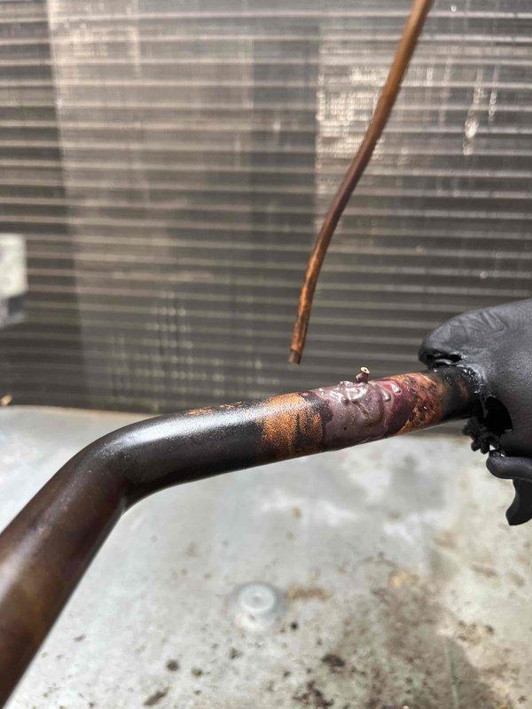 Responded to callback for kitchen AC unit not cooling following previous leak repair. Upon inspection, discovered the small TXV line connecting to the suction line had failed and blown off. Failure attributed to embrittlement of the line from previous brazing repair on the suction line crack, causing the line to become too brittle to withstand system pressure. 

Implemented temporary solution by disconnecting the affected compressor and bypassing its low pressure switch to restore partial cooling capacity with the remaining compressor. This allows the unit to provide cooling while scheduling the permanent repair. 

Full repair will require approximately four hours and involves either reconnecting the TXV line properly or upgrading the TXV assembly to eliminate the need for brazing the small diameter line. Photos documented the failed connection point and affected components. Unit currently operational with single compressor configuration pending scheduled repair completion.
