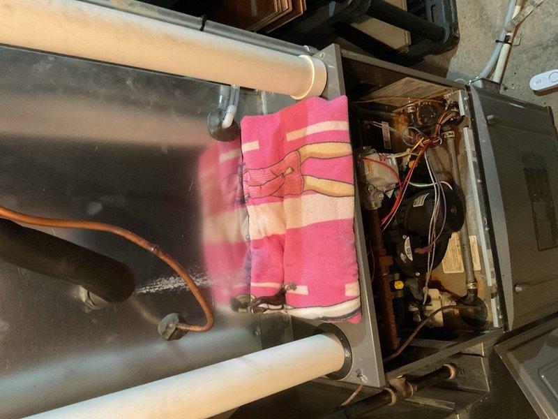 Completed annual cooling maintenance on residential AC system as part of rewards membership agreement. During inspection, discovered significant long-term condensate intrusion issue on 2015 Rheem furnace originating from combustion air intake piping, causing moisture accumulation in blower compartment affecting blower deck and control board. Previous technician had recommended complete vent re-piping; instead installed Fernco-style drain-enabled fitting on intake pipe with braided drain tube and verified proper drainage function by water testing at outdoor intake. AC system (replaced 2022 or 2024, exact year unconfirmed) showed acceptable performance at time of service with normal operating pressures and 19-20°F temperature split across evaporator coil. However, homeowner reported annual refrigerant loss requiring repeated additions, with previous service company identifying suspected evaporator coil leak. Despite normal readings during current visit, historical refrigerant loss patter