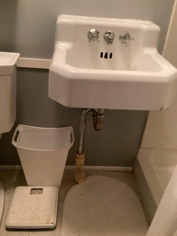 Responded to service call for downstairs bathroom sink with severely reduced water flow. Upon inspection of the white wall-mounted sink with chrome cross-handle faucets, confirmed minimal water output from the faucet. Diagnosed issue as clogged aerator restricting water flow. Removed aerator from faucet spout, cleared debris and sediment buildup, and reinstalled aerator. Tested water flow and verified full pressure restoration to the fixture.