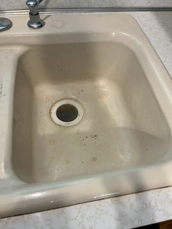 Responded to service call for kitchen sink backing up and not draining properly. Upon arrival, performed diagnostic inspection and identified blockage caused by accumulation of food debris, soap scum, and sludge restricting the drain line. Utilized flex shaft cable machine to clear the obstruction, running the cable through the full length of the drain line while flushing with hot water to break up buildup. Located and cleared the blockage at approximately 15 feet into the line, successfully restoring proper drainage flow. Reassembled all drain components and conducted thorough testing by filling and dumping both sink bays to verify complete clearance. Confirmed all drainage functioning properly with no leaks detected at any connections. System restored to full working order.