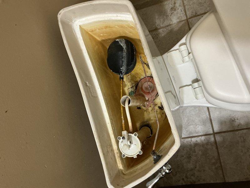 Completed comprehensive plumbing inspection of residential property. Inspected toilet tank internal components, noting significant mineral buildup and discoloration requiring future maintenance attention, and examined under-sink plumbing assembly with PVC and copper drainage configuration, verifying proper trap installation and connections.