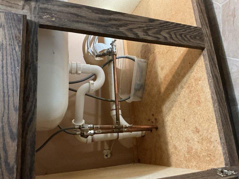 Completed comprehensive plumbing inspection of residential property. Inspected toilet tank internal components, noting significant mineral buildup and discoloration requiring future maintenance attention, and examined under-sink plumbing assembly with PVC and copper drainage configuration, verifying proper trap installation and connections.