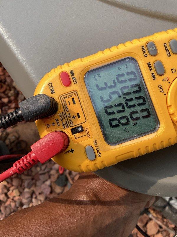 Completed annual cooling maintenance tune-up on residential AC system as part of membership agreement. During inspection, identified fluctuating refrigerant pressures and measured 14-degree temperature split across the evaporator coil, which falls below the optimal 15-20 degree range for efficient cooling operation. Documented findings with diagnostic photos of attic-mounted air handler unit and multimeter readings; advised customer of performance concerns and recommended follow-up with original installing contractor to address refrigerant charge and system efficiency issues.