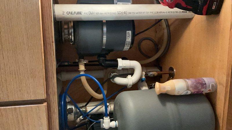 Responded to service call for kitchen sink and faucet installation. Customer supplied undermount sink and faucet for installation in kitchen with granite countertop. Coordinated with countertop company for proper undermount sink installation, as specialized adhesive and mounting procedures are required for secure attachment to underside of stone countertop. Provided estimate for complete kitchen faucet installation and drain reconnection work. Documented existing kitchen layout featuring wood cabinetry, granite countertops, and stainless appliances. Inspected under-sink cabinet area containing existing water treatment system with pressure tank, filtration equipment, and associated PVC plumbing connections. Confirmed adequate clearance and access for new fixture installations while maintaining existing water treatment infrastructure. Work pending coordination with countertop installer for sink mounting completion before final plumbing connections can be established.