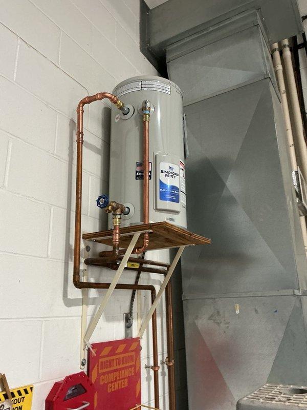 Removed and disposed of existing failed water heater. Supplied and installed new 12-gallon Bradford White water heater on wall-mounted wooden platform. Connected copper supply lines with brass fittings and installed blue-handled ball valve for system shut-off control. Reconnected temperature and pressure relief valve and added new drain line to unit, as previous installation lacked proper drainage. Set thermostat to match previous unit's temperature setting. Installation includes manufacturer warranty and 1-year parts and labor warranty. System tested and operational upon completion.