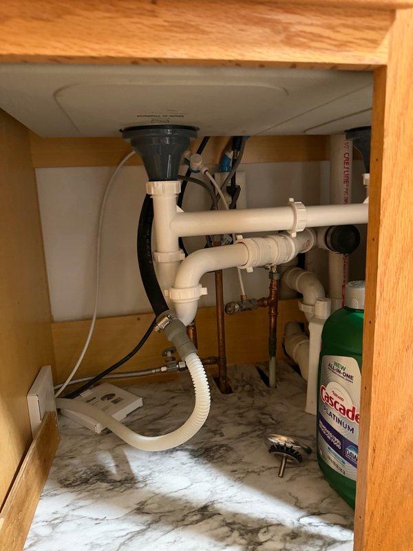 Responded to callback for dirty water accumulating in dishwasher following garbage disposal removal. Upon inspection, identified that dishwasher drain line lacked proper high loop configuration, allowing wastewater to siphon back into the appliance. Installed proper high loop on dishwasher drain line under sink to prevent backflow and ensure complete drainage from the line. Tested system to verify proper operation and drainage.