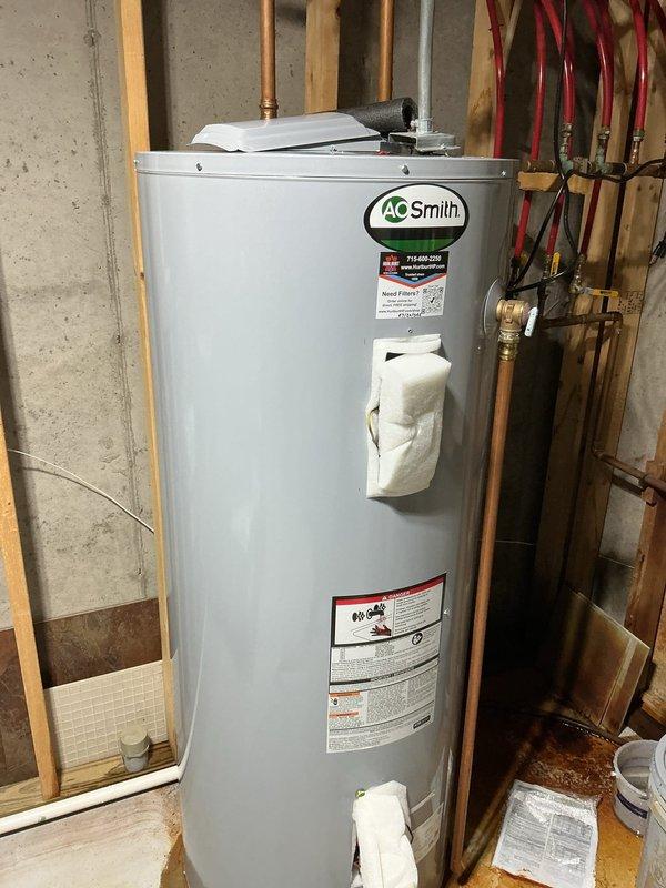 Responded to emergency call for ruptured 80-gallon electric water heater that caused major water leak into basement. The failed unit was an AO Smith model that had catastrophically failed, requiring immediate replacement to prevent further water damage. Coordinated with water damage restoration company for basement remediation.

Removed and disposed of failed 80-gallon electric water heater. Installed replacement 80-gallon AO Smith electric water heater under manufacturer warranty coverage. Verified all electrical connections at terminal block were properly secured and grounded according to code requirements. Connected hot and cold water supply lines using copper piping with appropriate brass fittings and shut-off valves. Installed red PEX expansion loops on supply lines for thermal expansion protection. Tested all plumbing connections for leaks and verified proper water flow. Energized unit and confirmed heating elements were functioning correctly. Documented installation with photos 