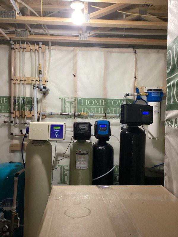Installed calcite neutralizer system and repiped water treatment equipment in proper sequence: nitrate filter, neutralizer, water softener, then to house supply. Reconfigured existing system layout by swapping unit order to optimize water treatment process and ensure correct filtration staging for residential water quality improvement.