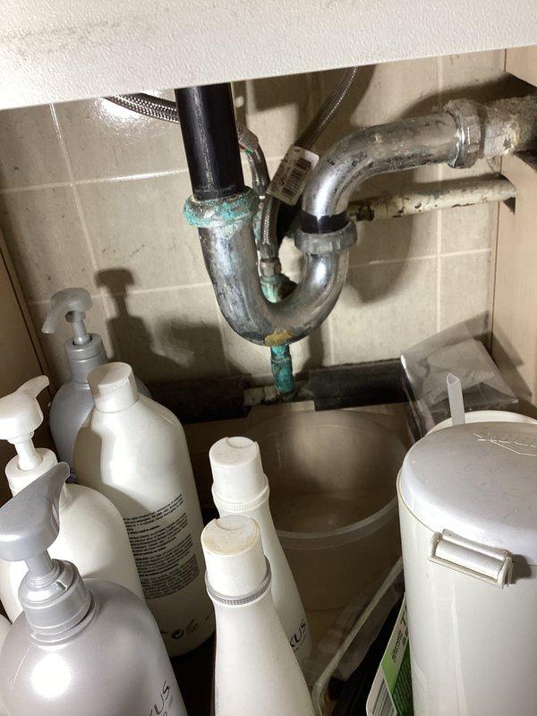 Completed biannual plumbing inspection with focus on water heater and overall system assessment. Inspected under-sink plumbing assembly, noting P-trap configuration with chrome-plated pipes showing age-appropriate wear and minor corrosion at connection points. Observed copper oxidation and verdigris formation at joints, typical of older installations but not requiring immediate intervention. Verified drain assembly and flexible supply lines remain functional. 

Coordinated HVAC system inspection during same visit, examining copper refrigerant line connections and service valves. All components operating within normal parameters with no new issues identified. Annual inspection confirmed system integrity maintained through proper homeowner care.