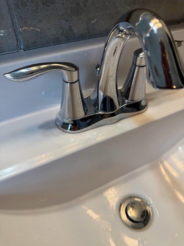 Responded to service call for loose bathroom faucet handle on chrome two-handle centerset faucet assembly. Upon inspection, determined that the handle had become unspun from its mounting base, causing it to detach during normal operation. Tightened and secured the faucet handle back onto the valve stem, restoring proper function and stability to the fixture.