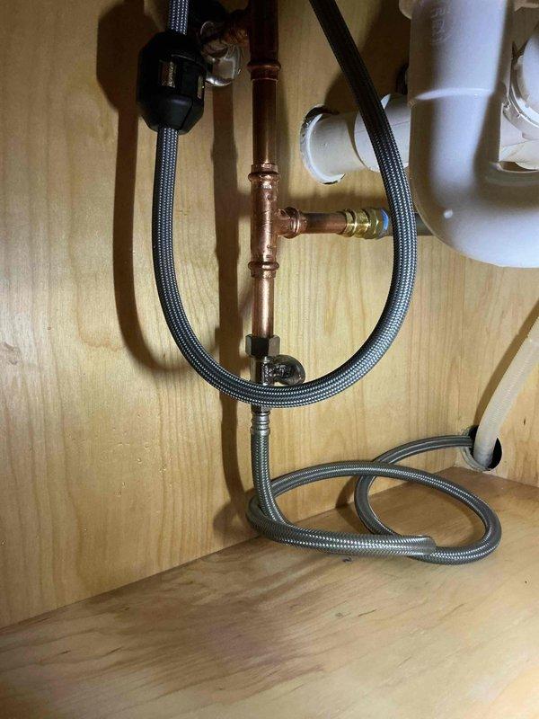 Responded to water leak under bar sink in basement. Upon inspection, discovered that a hammer arrestor previously installed had failed at the 1/2 inch polypropylene adapter connection, causing active water leakage. Removed the defective hammer arrestor assembly and replaced the failed PP adapter and associated components. Installed new braided flexible supply lines and verified all compression fittings on copper piping were secure. Tested system under full water pressure to confirm leak was resolved. Referred water damage restoration to appropriate contractor. Work performed under warranty coverage.