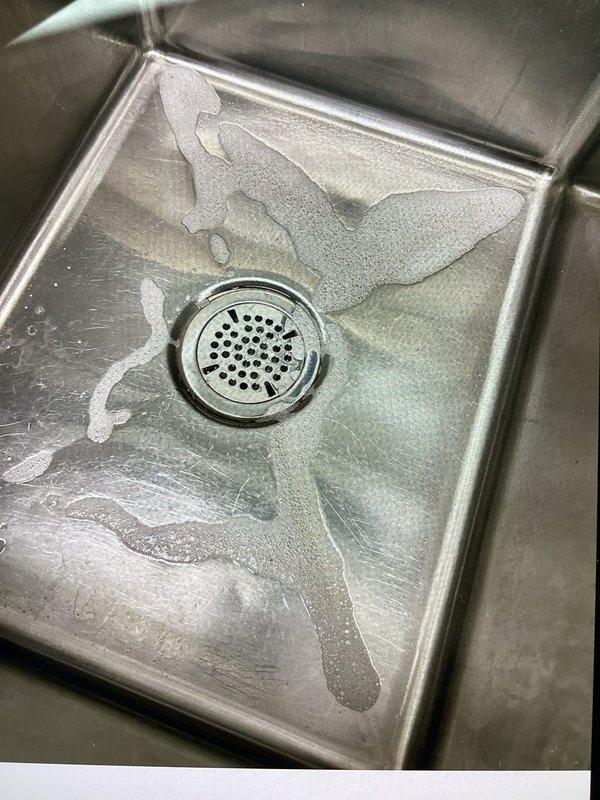 Responded to a commercial plumbing service call for two active leaks: one at the drain of the first basin in a three-compartment sink system and another at the water supply line quick-connect fitting serving an espresso machine. Upon inspection, successfully resolved the supply line leak by readjusting the connection to achieve proper seal. Identified the basket strainer in the sink drain as the source of the second leak, requiring replacement due to failed seal integrity. Documented the existing conditions with photographs and advised that the replacement basket strainer part needs to be ordered for final repair completion.