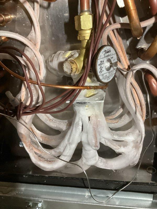 Responded to callback on recently installed Unico AC system with cooling complaints and thermostat temperature reading issues. Upon inspection, discovered system was short-cycling with condenser shutting off due to low pressure cutout. Diagnosed metering device freezing up at evaporator coil. Root cause identified as mismatched TXV—existing unit equipped with 3-ton valve while condenser and Unico air handler are both 4-ton capacity, causing improper refrigerant metering and system failure. Recommended replacement with properly sized 4-ton TXV kit to match system tonnage and restore proper operation.