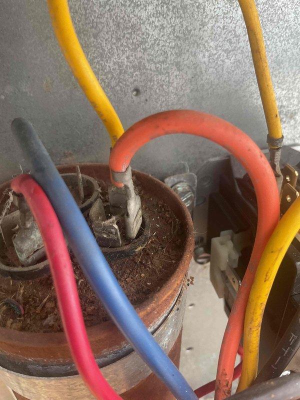 Responded to no cooling call and found system low on refrigerant with capacitor reading 44 microfarads, indicating failure. Upon inspection, discovered severe corrosion and debris accumulation inside capacitor housing with rust throughout electrical connections. Due to unit age and extent of deterioration, recommended full system replacement while providing estimate for capacitor replacement as alternative option.