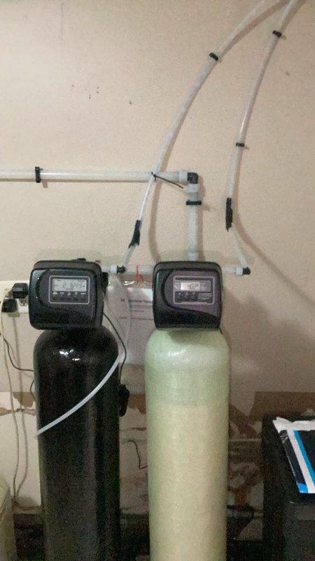 Performed follow-up water quality testing two months after initial water treatment system installation. Testing revealed elevated pH levels caused by inadequate well pump flow to the neutralizer tank, resulting in stagnant media bed and potential clumping. Flushed both the neutralizer and water softener units to address the issue. During system evaluation, observed stable pressure during softener operation, but insufficient media movement and pressure loss when neutralizer was flushing, confirming inadequate water supply from well pump. Left neutralizer in bypass mode to restore system functionality. Retested water pH levels, which returned to raw water baseline of 6.0-6.5 pH. Recommended evaluating well pump capacity, considering installation of smaller capacity neutralizer tank requiring reduced water volume, or removing neutralizer from system entirely to match available water supply.