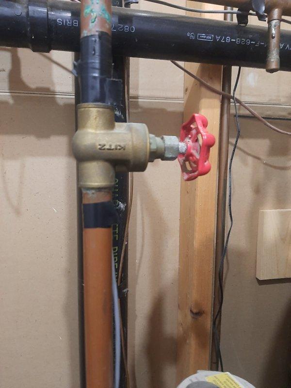 Performed on-site evaluation and provided estimate for replacement of three isolation valves in main water supply system. Assessment included one non-functional valve located before the water meter on the main line, one valve after the meter, and one valve on the hot water heater supply line. All valves were readily accessible in the utility area, with straightforward installation conditions noted. The existing plumbing assembly consisted of mixed materials including brass fittings, copper piping, and galvanized connections showing typical age-related wear and corrosion. Documented current conditions with photographs showing the T-fitting configuration with red valve handle at the main line and the vertical meter assembly. Work scope confirmed as routine valve replacement with no complications anticipated due to clear access and standard pipe configurations.