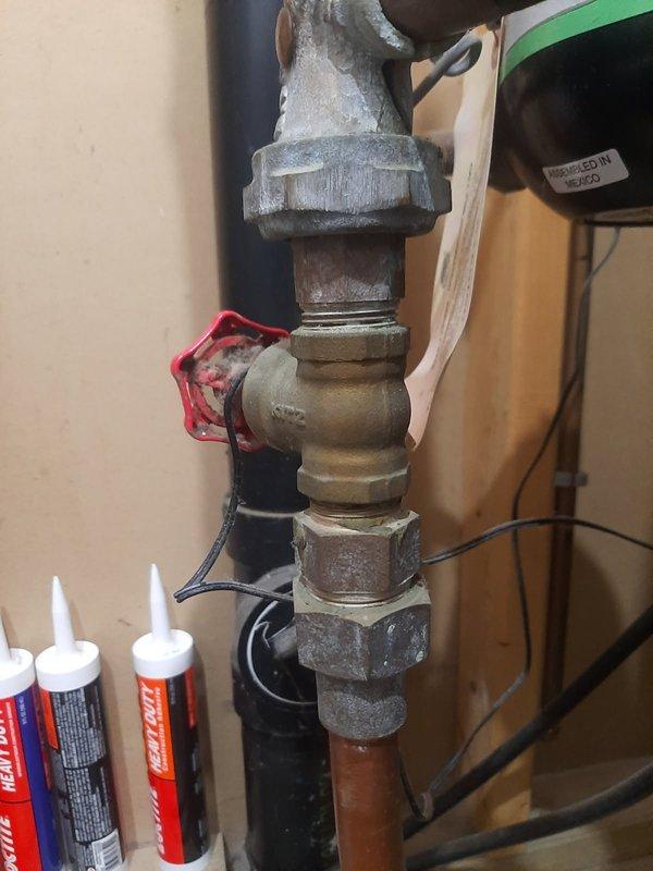 Performed on-site evaluation and provided estimate for replacement of three isolation valves in main water supply system. Assessment included one non-functional valve located before the water meter on the main line, one valve after the meter, and one valve on the hot water heater supply line. All valves were readily accessible in the utility area, with straightforward installation conditions noted. The existing plumbing assembly consisted of mixed materials including brass fittings, copper piping, and galvanized connections showing typical age-related wear and corrosion. Documented current conditions with photographs showing the T-fitting configuration with red valve handle at the main line and the vertical meter assembly. Work scope confirmed as routine valve replacement with no complications anticipated due to clear access and standard pipe configurations.