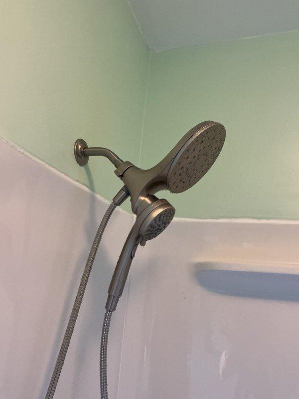Responded to low water pressure complaint in upstairs bathroom shower. Upon inspection, removed and examined dual shower head system, including rainfall head and handheld unit. Found no debris or blockages in shower heads or supply lines. Determined that factory-installed flow restrictor was limiting water pressure to the fixture. Verified adequate water pressure at shower arm connection, confirming well system and supply plumbing functioning properly. Discussed option to remove flow restrictor with customer, explaining potential risks of debris accumulation without restriction in place. Customer elected to maintain current configuration with flow restrictor installed.