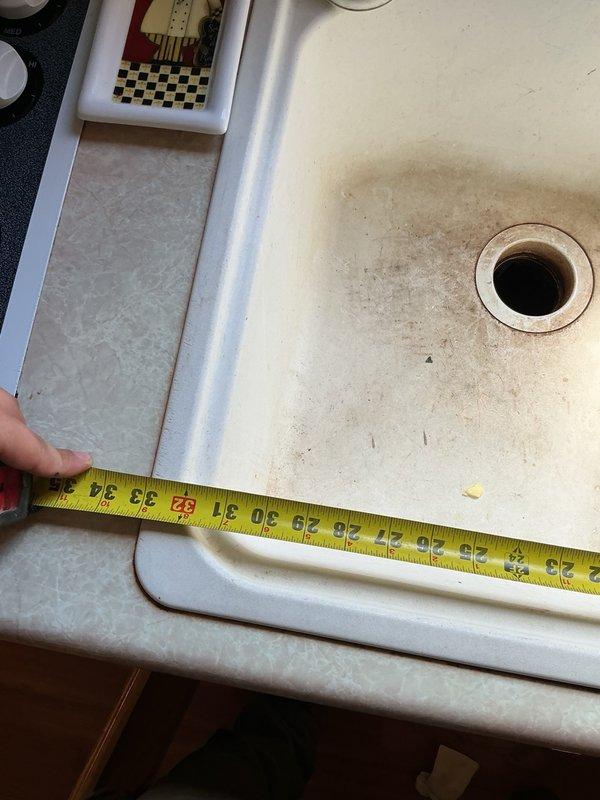 Conducted site assessment for kitchen sink replacement project. Customer currently has dual-hole sink configuration and wishes to convert to single-hole sink setup. Took measurements of existing sink basin and documented current plumbing configuration, including garbage disposal unit on left side and white PVC drain assembly with P-trap on right side. Provided estimate for complete sink replacement and re-piping of drain assembly beneath sink. Customer will source preferred sink unit from local supplier and schedule installation upon acquisition. Future scope of work will include removal of existing dual-hole sink, installation of new single-hole sink, modification of drain plumbing to accommodate new configuration, and reconnection of garbage disposal unit to updated drain system.