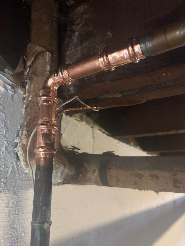 Responded to service call addressing multiple plumbing issues identified during home inspection. Repaired water leak at main supply pipe above meter near basement ceiling using compression fittings on copper piping. Evaluated and serviced basement laundry sink faucet experiencing difficulty with operation, performing necessary adjustments to restore proper function. Inspected upstairs toilet exhibiting instability and rocking motion, assessed mounting and wax ring condition. Documented existing plumbing infrastructure with photographic evidence showing copper supply lines and bathroom fixtures. Work performed in accordance with Minneapolis municipal code requirements for licensed plumbing contractors, with permit coordination initiated for required safety inspections and final approval.