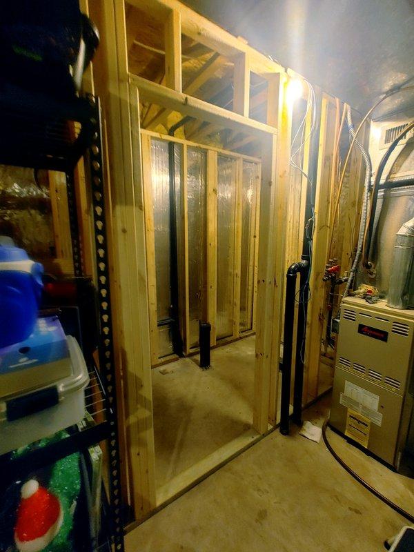 Completed rough-in plumbing work for new bathroom installation in unfinished basement area. Installed water supply lines to toilet and lavatory locations, routing copper or PEX piping through framed wall cavities to appropriate fixture positions. Performed rough-in plumbing for 48-inch shower enclosure, including hot and cold water supply lines and drain waste vent system through concrete floor penetration. All supply lines stubbed out at proper heights and locations per plumbing code requirements for future fixture installation. Chrome faucet supplied for shower installation by finishing contractor. Rough-in work coordinated with ongoing construction framing visible in mechanical utility space.