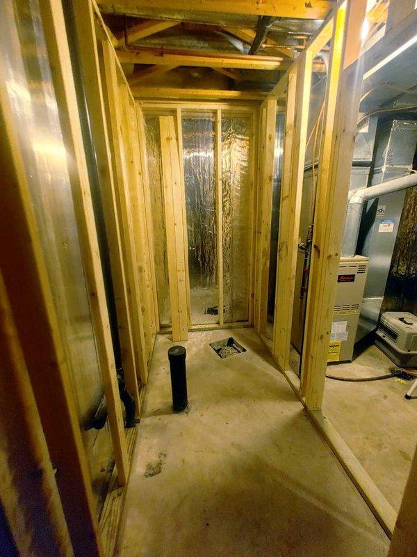 Completed rough-in plumbing work for new bathroom installation in unfinished basement area. Installed water supply lines to toilet and lavatory locations, routing copper or PEX piping through framed wall cavities to appropriate fixture positions. Performed rough-in plumbing for 48-inch shower enclosure, including hot and cold water supply lines and drain waste vent system through concrete floor penetration. All supply lines stubbed out at proper heights and locations per plumbing code requirements for future fixture installation. Chrome faucet supplied for shower installation by finishing contractor. Rough-in work coordinated with ongoing construction framing visible in mechanical utility space.