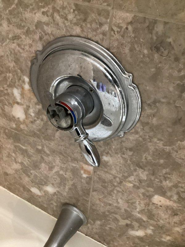 Responded to a loose shower handle complaint in a residential bathroom. Upon inspection, confirmed the shower valve handle had become loose from normal wear and use. Tightened the handle assembly at the valve stem to restore proper secure operation. The chrome-finished lever-style control with decorative escutcheon plate was properly secured to prevent further movement. Verified handle operated smoothly through full range of motion after tightening. Hot and cold water indicators remained properly aligned. No additional repairs or component replacement required.