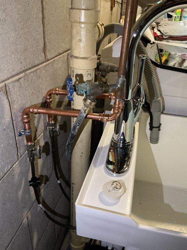 Completed installation of new laundry utility sink with chrome pull-down faucet in basement utility area. Installed new 3/4" press ball valve on main water line serving the entire residence, coordinating municipal water shutoff for safe replacement. Provided and installed new shutoff valves serving the laundry faucet, new P-trap assembly, and replacement floor drain cover. All copper piping connections were secured with proper fittings and tested for leaks. Upon completion, conducted full operational testing of all fixtures and valves to verify proper function and confirm leak-free installation throughout the system.