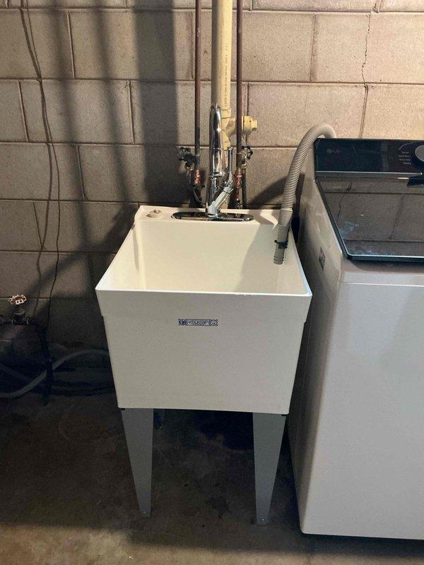 Completed installation of new laundry utility sink with chrome pull-down faucet in basement utility area. Installed new 3/4" press ball valve on main water line serving the entire residence, coordinating municipal water shutoff for safe replacement. Provided and installed new shutoff valves serving the laundry faucet, new P-trap assembly, and replacement floor drain cover. All copper piping connections were secured with proper fittings and tested for leaks. Upon completion, conducted full operational testing of all fixtures and valves to verify proper function and confirm leak-free installation throughout the system.