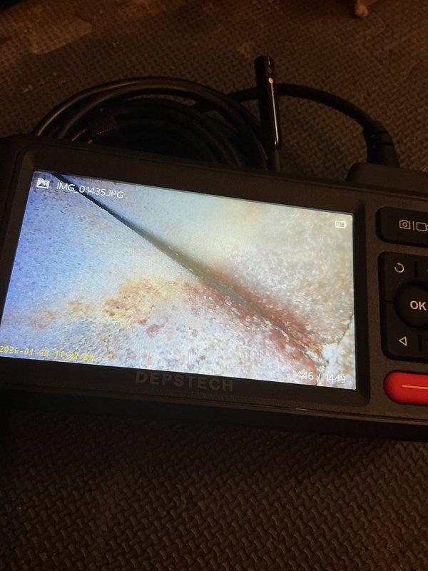 Responded to no cooling complaint on 20-year-old air conditioning system that had previously iced over. Upon arrival, unit was thawed and operational but failing to reach desired temperature setpoint. Performed diagnostic evaluation and identified system was low on R22 refrigerant. Conducted borescope inspection of evaporator coil, documenting interior condition with digital imaging that revealed moisture accumulation and oxidation staining on coil surfaces. Given the age of the unit, obsolete refrigerant type, and current system condition, recommended comfort advisor consultation for replacement options rather than repair of aging equipment.