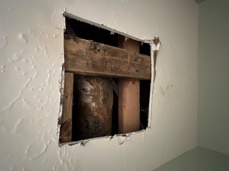 Responded to main floor toilet leak causing water damage to basement ceiling below. Upon inspection, confirmed water dripping into basement when toilet was flushed. Diagnosed leak originating from toilet base or wax ring seal. Created access opening in basement ceiling drywall to assess extent of water damage and identify leak source from above. Documented water staining on wooden framing members and structural components. Provided estimate for toilet removal, wax ring replacement, flange inspection, and reinstallation to resolve active leak and prevent further water intrusion.
