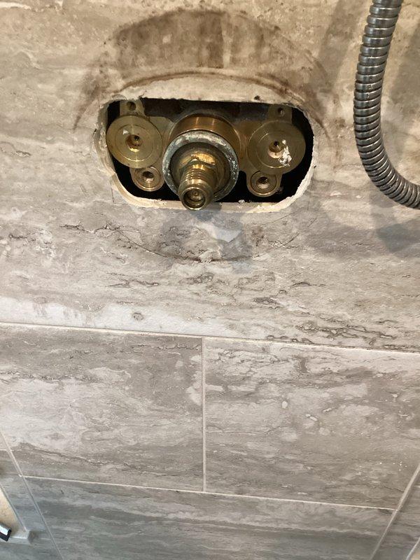 Responded to service call for shower volume control issues. Accessed shower valve assembly through tiled bathroom wall opening. After initial assessment, contacted Grohe technical support to verify correct replacement parts specifications. Corrected parts sourcing and supplied two new Grohe shower volume control cartridges. Removed existing cartridges showing mineral deposits and corrosion. Installed replacement cartridges into brass valve bodies. Tested both shower controls for proper volume regulation and operation. Inspected all connections for leaks. Cleaned work area and removed debris. System restored to full functionality with one-year parts and labor warranty provided.