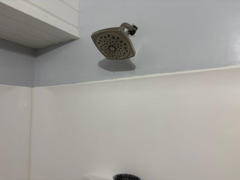 Responded to service call for Kohler shower system experiencing low water pressure and temperature control issues. Upon inspection, found shower valve was difficult to operate and inconsistent in maintaining desired water temperature. Assessed existing brushed nickel shower fixtures including single-handle valve assembly and diverter spout. Documented current installation with photos showing wall-mounted faucet assembly with circular escutcheon plate and overhead showerhead with multi-spray nozzles. Provided customer with detailed estimates for fixture replacement and valve repair options to resolve operational concerns.