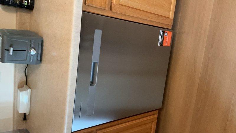 Installed customer-supplied stainless steel dishwasher in residential kitchen beneath existing countertop. Connected water supply line, drain hose, and electrical connections per manufacturer specifications, ensuring proper fit within cabinetry opening and verifying operational functionality upon completion.