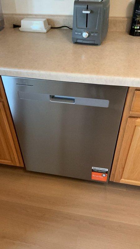 Installed customer-supplied stainless steel dishwasher in residential kitchen beneath existing countertop. Connected water supply line, drain hose, and electrical connections per manufacturer specifications, ensuring proper fit within cabinetry opening and verifying operational functionality upon completion.