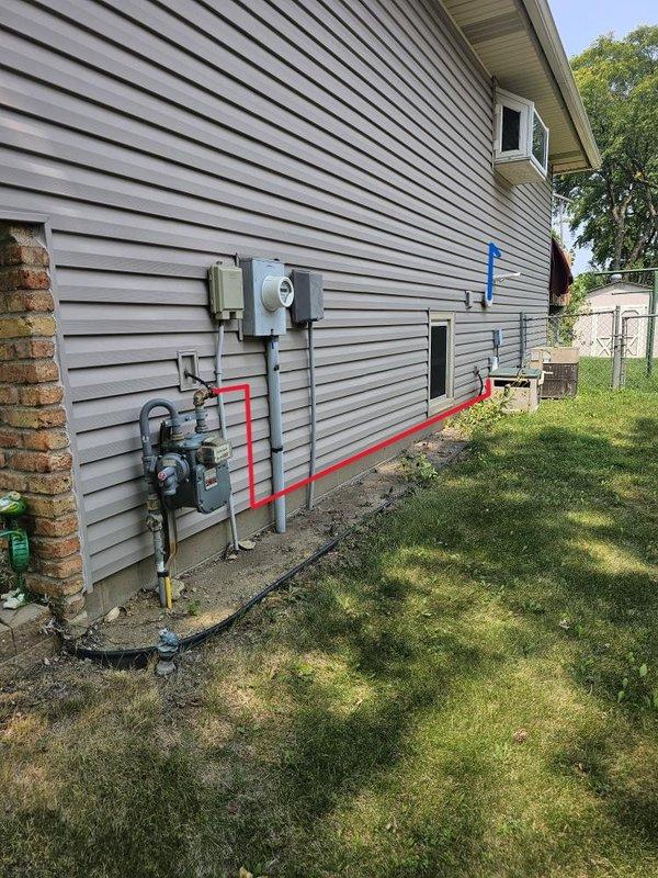 Completed code correction work for tankless water heater installation requiring gas line upsizing and concentric venting modifications. Installed new 1/2" soft copper gas line running approximately 80 feet from the meter along exterior siding into the mechanical room, replacing undersized 3/8" line. Added dedicated regulator positioned 10 feet from tankless unit and connected heater to its own gas supply line. Capped off original 1/2" black iron tee connection point. Modified concentric vent kit by snorkeling exhaust side 3 feet above furnace intake to meet code clearance requirements. Secured all new gas piping to structure, applied high-pressure warning labels at appropriate locations, and performed complete leak check of all connections. System tested and verified operational with no leaks detected. Unit left in service.