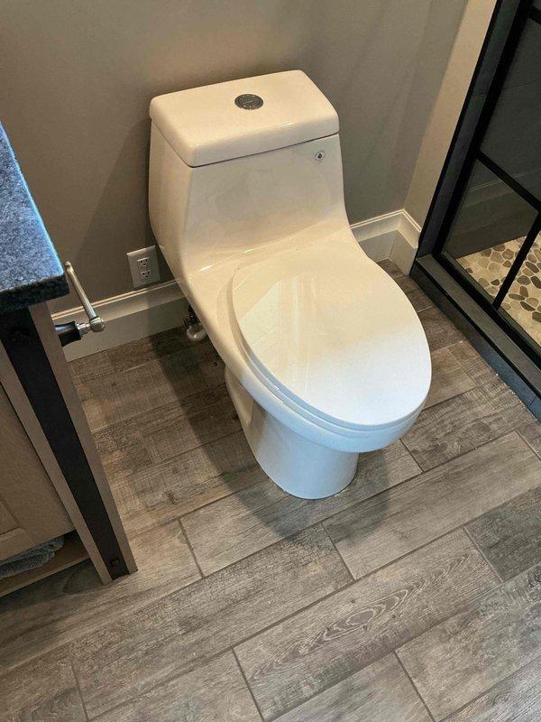 Responded to service call for leaking toilet in residential bathroom. Upon inspection, identified internal mechanical failure in three-year-old Toto one-piece toilet causing persistent water leak. Removed and disposed of failed unit, then installed new white one-piece toilet with dual-flush mechanism. Ensured proper seating on wax ring, secured mounting bolts, connected water supply line, and tested for leaks and proper flush operation. Verified all functions working correctly before completing installation.