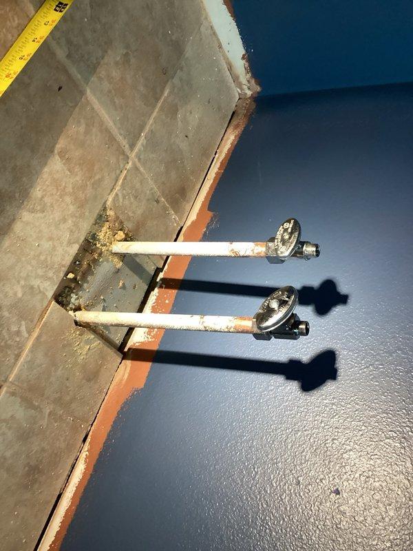 Installed two chrome angle stop shut-off valves with compression fittings on water supply lines serving bathroom vanity. The valves were mounted on vertical pipes emerging from the floor against the wall, providing individual water control for hot and cold supply lines. Installation included proper compression fitting connections to ensure leak-free operation.