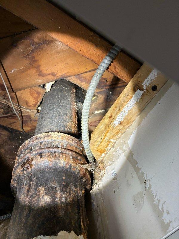 Responded to water leak in basement involving cast iron sewer pipe. Upon inspection, discovered the main drain stack connecting to kitchen drain was severely compromised with extensive cracking extending from the base up to the tee connection point. Evidence indicated previous repair attempt using JB Weld compound on the tee fitting to address an earlier leak. Identified new pinhole formation in addition to existing cracks throughout the stack section. Documented conditions with photographs showing advanced deterioration of cast iron piping, visible corrosion, and structural integrity concerns. Coordinated follow-up estimate appointment for comprehensive repair recommendations prior to scheduled property inspection.