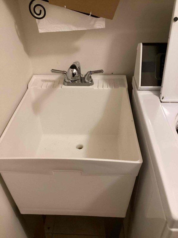Responded to service call for leaking faucet on utility sink in laundry area. Customer elected to supply their own replacement faucet fixture for installation. Successfully removed existing chrome two-handle centerset faucet from white utility sink basin and installed customer-provided replacement unit. Verified proper water supply connections, tested for leaks, and confirmed full functionality of both hot and cold water handles with adequate flow and drainage.