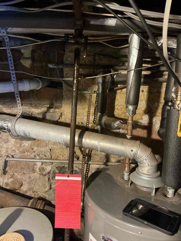 Responded to gas odor complaint at tanked water heater following previous unsuccessful leak detection attempt. Conducted systematic inspection beginning at main gas shut-off valve to water heater. Located gas leak at shut-off valve connection point that had been previously overlooked. Documented findings with photographs showing valve assembly, piping connections, and surrounding plumbing infrastructure. Coordinated with HVAC department for immediate repair of compromised gas valve and associated piping to eliminate safety hazard and restore safe operation of water heating system.
