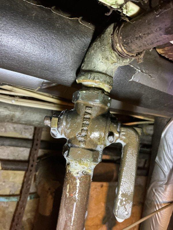 Responded to gas odor complaint at tanked water heater following previous unsuccessful leak detection attempt. Conducted systematic inspection beginning at main gas shut-off valve to water heater. Located gas leak at shut-off valve connection point that had been previously overlooked. Documented findings with photographs showing valve assembly, piping connections, and surrounding plumbing infrastructure. Coordinated with HVAC department for immediate repair of compromised gas valve and associated piping to eliminate safety hazard and restore safe operation of water heating system.