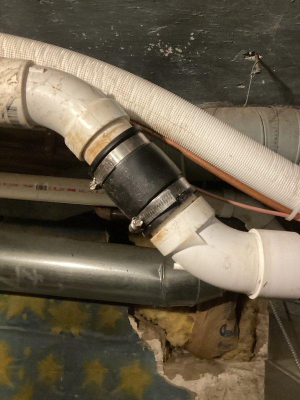 Responded to kitchen drain backup issue where water was backing up through pipe under sink during use. Successfully cleared clogged kitchen drain by running snake through drainage system to remove obstruction. Documented existing plumbing configuration including PVC drainage pipes, coupling connections, and insulated supply lines in crawlspace area beneath sink for service records.