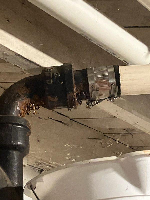Responded to basement water leak occurring when air conditioning system was in operation. Upon inspection, identified severely corroded cast iron drain pipe under basement stairs with visible hole causing water discharge. Extensive rust damage and deterioration observed on cast iron plumbing connections and fittings. Documented condition of compromised piping system with photographs showing advanced corrosion on metal components and deteriorated pipe connections. Customer also reported water pooling in basement after using kitchen and bathroom sinks, consistent with failed drain line. Advised customer of need for cast iron pipe replacement due to extent of deterioration and recommended obtaining estimate for complete cast iron repipe to address systemic corrosion issues throughout drainage system.