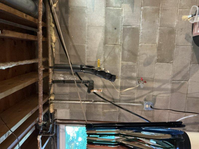 Responded to emergency call for leaking water heater causing flooding in basement. Upon arrival, inspected 5-year-old tank-style water heater and confirmed active leak originating from bottom of unit. Determined water heater had failed prematurely and was beyond repair. Removed defective water heater from premises to prevent further water damage to basement floor and surrounding area.