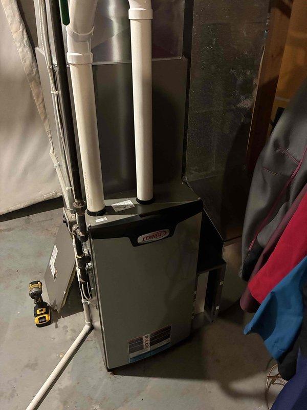 Responded to water leakage complaint from Lennox furnace unit installed two years prior. Upon inspection, discovered evaporator coil drain pan was full and overflowing onto floor. Identified blockage in MPT to barb fitting at drain pan outlet caused by accumulated debris and gunk. Removed and cleaned elbow fitting, flushed remaining sediment from drain pan, and verified proper drainage flow was restored. System operational with condensate draining correctly.