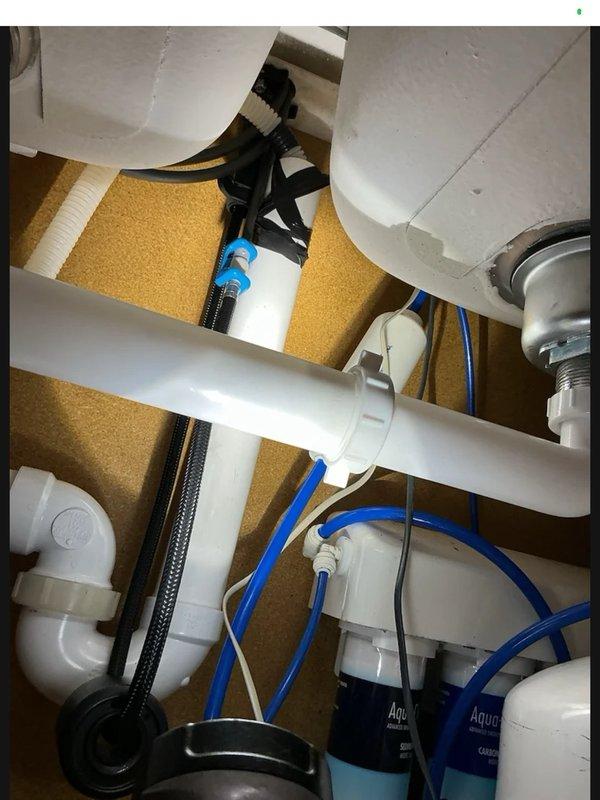 Responded to return visit for leak under kitchen sink. Upon inspection, identified loose slip nut on continuous waste assembly causing dripping. Tightened all slip nuts on drain connections and verified proper seal. Ran water through both sink drains to test system and confirmed leak was resolved with no further dripping observed.