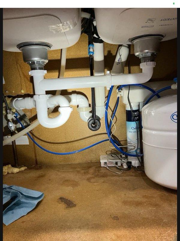 Responded to return visit for leak under kitchen sink. Upon inspection, identified loose slip nut on continuous waste assembly causing dripping. Tightened all slip nuts on drain connections and verified proper seal. Ran water through both sink drains to test system and confirmed leak was resolved with no further dripping observed.