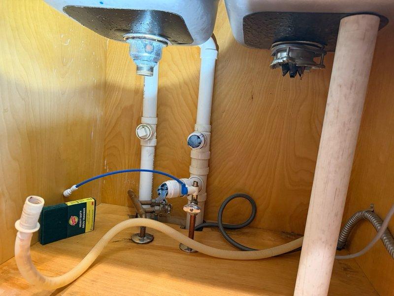 Disconnected kitchen sink, faucet, garbage disposal, and reverse osmosis system in preparation for new sink installation. Returned following installation of new sink to reconnect garbage disposal, existing RO system, and all drain assemblies. All plumbing connections, supply lines, and drainage components were successfully reinstalled and tested for proper operation.